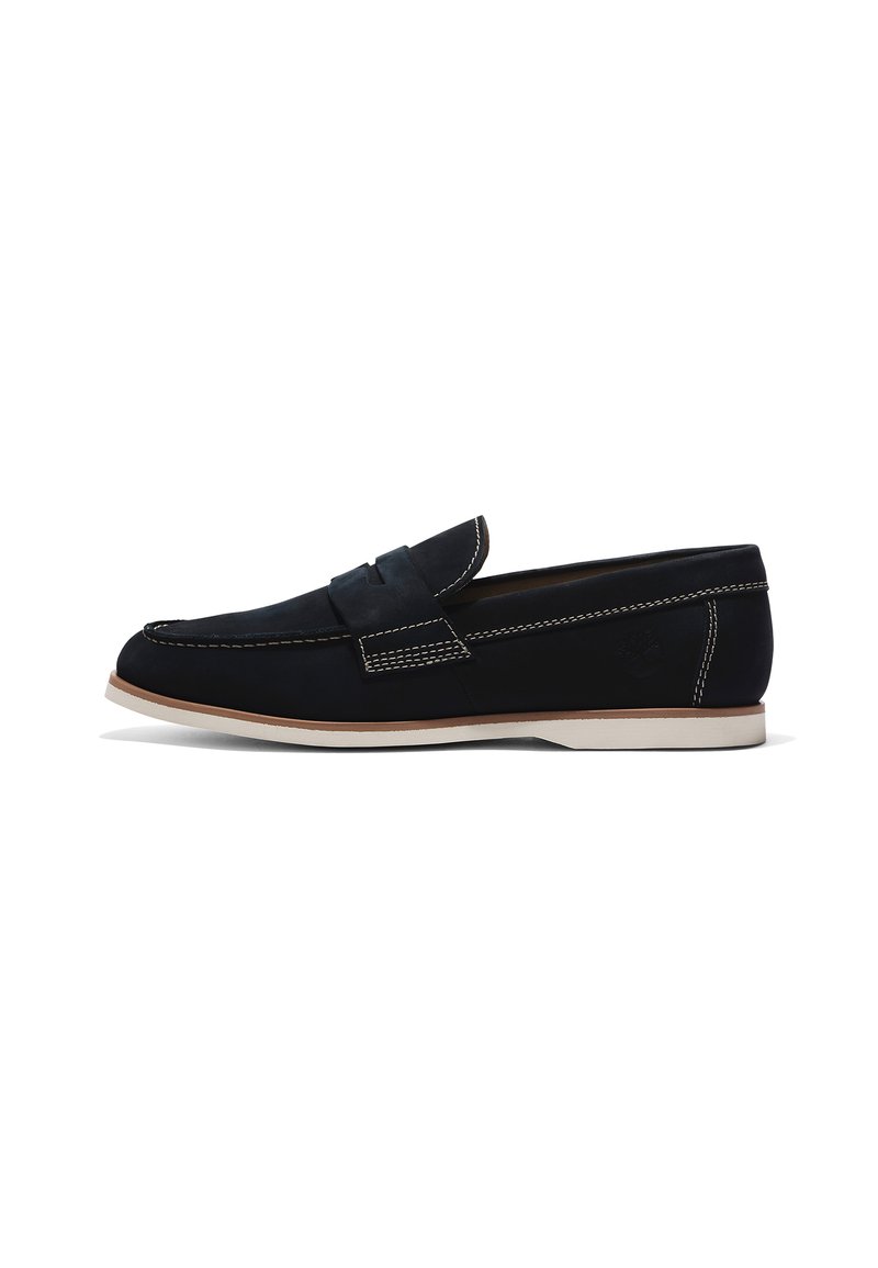 Mocasinés de ante negros con costuras contrastantes en blanco, diseño sin cordones, punta redondeada y suela de goma de color claro.