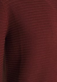 Bourgondische gebreide trui met een gestructureerd, geribbeld ontwerp, een zachte afwerking en een nauwsluitende pasvorm.