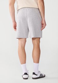 Gray cotton shorts with an elastic waistband, paired with white socks and black-accented athletic shoes. Smooth texture, casual fit.
