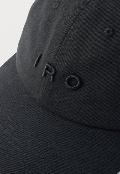 Casquette de baseball noire avec les lettres "IRO" brodées en relief et en noir sur le panneau avant, équipée d'œillets de ventilation cousus.