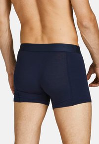 Marineblaue Herren-Boxershorts aus weichem Stoff, mit einem glatten Bund und einer enganliegenden Passform, die sich an den Körper anpasst.