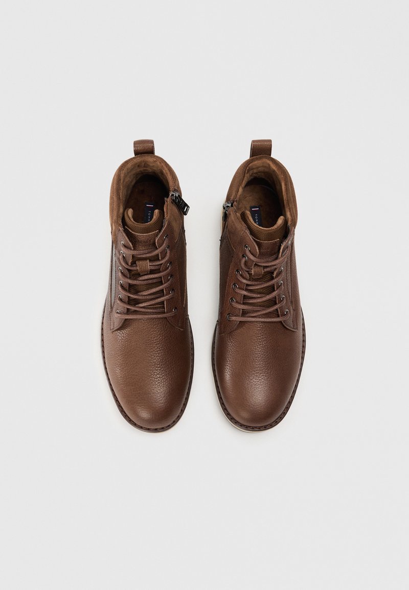 Bottes à lacets en cuir marron, avec une surface texturée, équipées d'une fermeture éclair sur le côté et d'accents en daim contrastants.