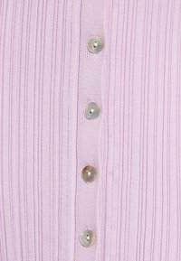 Tissu côtelé violet clair avec quatre boutons ronds brillants alignés verticalement au centre.