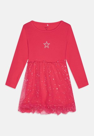 Czerwona sukienka dziecięca z długim rękawem, z motywem perłowej gwiazdy na piersi oraz błyszczącą spódnicą z tiulu z wzorem gwiazdek.