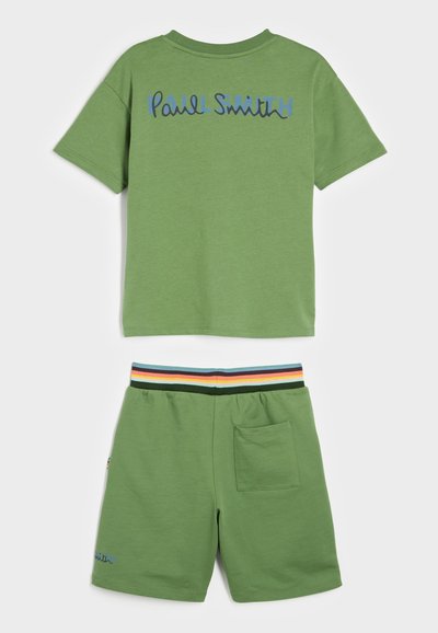 Zaļš kokvilnas T-krekls ar zilu "Paul Smith" logo aizmugurē, saskaņots ar atbilstošām šortiem, kuru josta ir daudzkrāsaina ar svītrām un sānu kabatu.