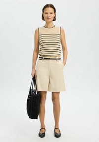 Beige striped sleeveless top with black lines, beige shorts, black woven tote bag, and black flats, featuring a straight and relaxed fit.
