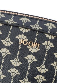 Portafoglio nero con texture, decorato con un motivo floreale dorato, con logo dorato "JOOP!" e chiusura a zip lungo il bordo superiore.