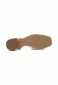 Beige heel shoe with a textured sole, featuring a woven upper material, open back design, and a smooth, rounded toe.