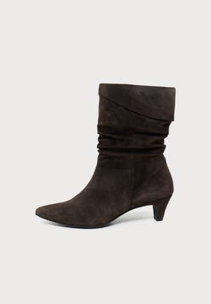 Dunkelbrauner Wildleder-Mittelkalf-Stiefel mit umgeschlagenem oberen Rand, schlaffem Schaft, spitzer Zehenpartie und niedrigem schrägem Absatz auf einfachem hellem Hintergrund.