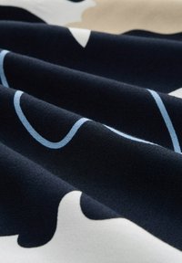 Stoff mit geschwungenen Mustern in Marineblau, Hellblau und Cremefarben. Das Material wirkt weich mit einer glatten Textur.