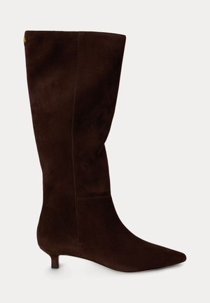 Bota de ante marrón oscuro hasta la rodilla con punta afilada y tacón bajo tipo kitten, mostrada de perfil sobre fondo neutro.