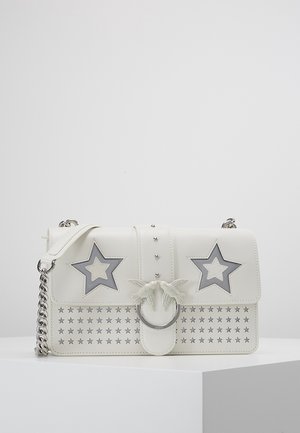 White leather shoulder bag with silver chain strap, star cutouts, and two birds on a circular metal clasp at the front.