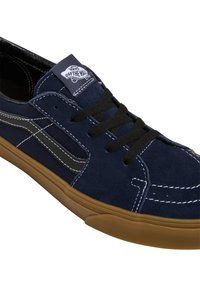 Baskets en daim bleu marine avec accents noirs et coutures blanches, dotées d'une semelle en caoutchouc et d'un design classique à lacets. Logo Vans sur la languette.