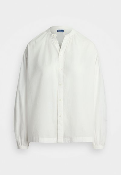 Bela bombažna srajca z okroglim izrezom, dolgimi rokavi, gatheranim pri manšetah, z gumbom in sproščenim krojem. Gladka tekstura, minimalistična zasnova.