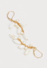 Boucles d'oreilles dorées présentant des perles ovales blanches et des perles, reliées par une chaîne avec un fermoir sécurisé. Texture lisse avec une finition polie.