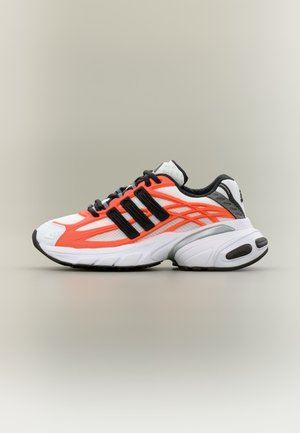 Sneakers atletica bianca e arancione con lacci neri e dettaglio nero a tre strisce, su uno sfondo neutro.