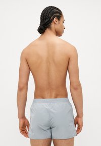 Grijze zwemshorts met een elastische tailleband, gemaakt van lichtgewicht materiaal, met een soepele textuur en een eenvoudig, klassiek ontwerp.