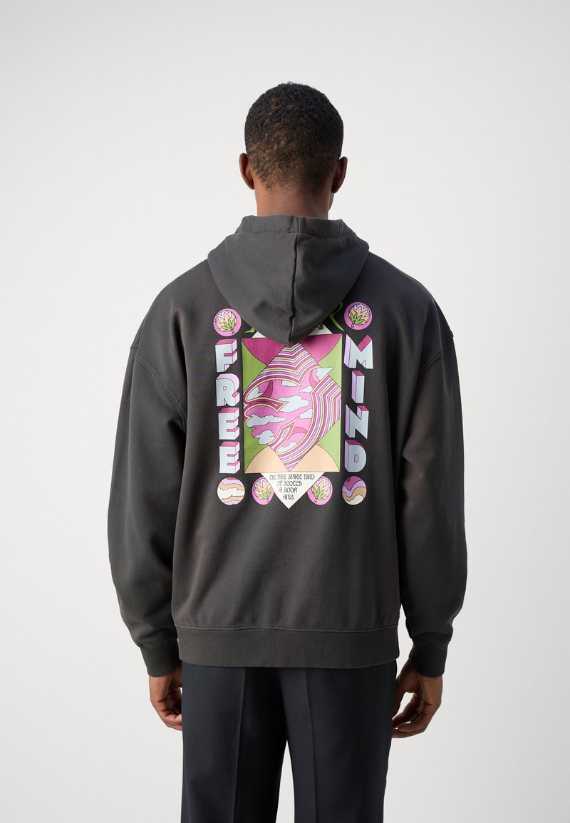 Zwarte hoodie met een groot grafisch ontwerp op de achterkant, met de tekst "FREE MINDS," een gestileerd gezicht en kleurrijke bladerenmotieven.