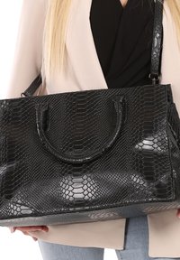 Zwarte handtas met textuur en een slangenhuidpatroon, twee ronde handvatten en een verstelbare schouderriem. Rechthoekige vorm met een gestructureerd ontwerp.