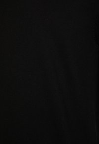 Černá pletená látka s hladkým povrchem a jednoduchým designem. Detailní pohled neobsahuje žádné viditelné vzory, hardware nebo akcenty.