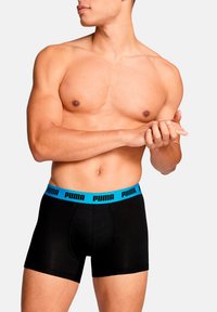 Schwarze Boxer-Shorts mit einem blauen Puma-Logo am Bund, die eine enge Passform und weichen, dehnbaren Stoff bieten, ideal für den täglichen Gebrauch.