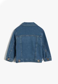 Chaqueta de mezclilla en azul medio con un acabado ligeramente desvaído. Cuenta con un cuello con solapa, dos detalles de botones en el dobladillo y un corte recto.