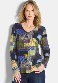 Langärmliges bedrucktes Oberteil mit V-Ausschnitt, das ein Patchwork aus bunten Mustern in Grün, Blau, Gelb, Lila und Tiermotiven zeigt.