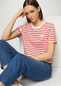 Rood-wit gestreepte T-shirt met een ronde hals en korte mouwen, gecombineerd met blauwe denim jeans. Minimalistisch logo detail op de borst.