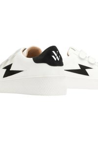 Des baskets en cuir blanc avec un talon en daim noir et un design d'éclair sur le côté. Des bandes Velcro améliorent la fonctionnalité. Semelle en caoutchouc texturée.