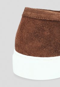 Brązowy zamszowy but wsuwany na obcasie z białą gumową podeszwą. Charakteryzuje się gładką teksturą i starannym szwem wzdłuż górnej krawędzi.