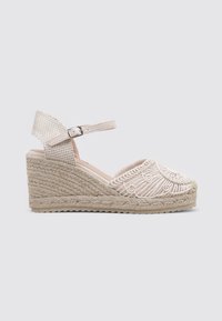 Sandalia de cuña en color beige con patrón bordado en la parte superior de tela, plataforma de yute trenzado y correa en el tobillo con detalle de hebilla.