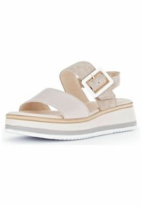 Tan and beige wedge sandals with wide adjustable straps, a white buckle, and a textured sole. Platform height is accentuated by a wood-like finish.