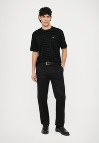Black geometric patterned short-sleeve t-shirt, crew neck, paired with black trousers and black shoes, slim fit, minimalist design, casual wear.