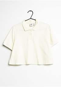 Skrócona żółta koszulka polo z miękkiej bawełny, z trzema guzikami na stójce i białym logo po lewej stronie klatki piersiowej. Krótkie rękawy.