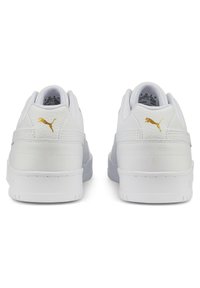 White sneakers featuring a smooth leather upper, textured accents, and a gold logo on the heel. Low design with a padded collar.