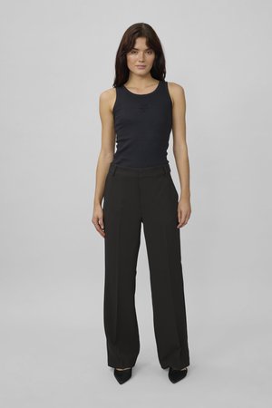 Black ribbed tank top with a round neckline paired with high-waisted black wide-leg trousers and pointed black heels.