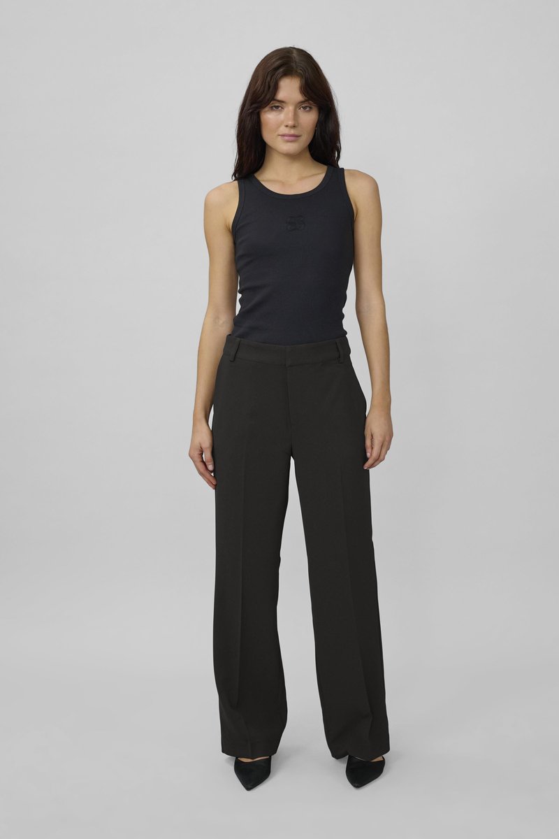 Top in maglia nera a coste con scollo rotondo abbinato a pantaloni neri a gamba larga e vita alta e tacchi neri a punta.