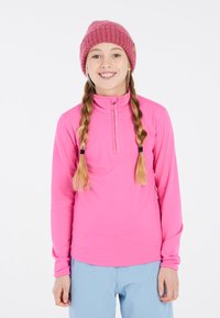 Top de manga larga fucsia con un collar con cremallera y mangas largas, combinado con pantalones azul claro. La tela es suave y elástica.
