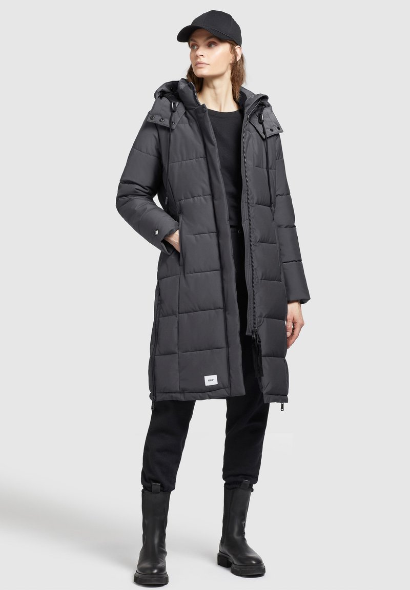 Langer, schwarzer Daunenmantel mit Kapuze, gestepptem Design, mit einem Frontreißverschluss, seitlichen Taschen und einem kleinen Brandingetikett am Saum.