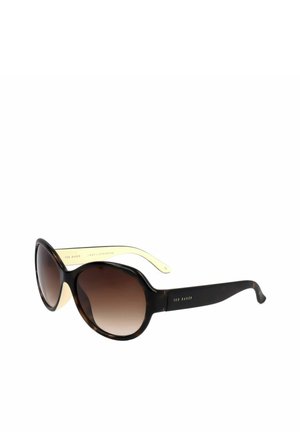 Occhiali da sole rotondi oversize con lenti sfumate marrone scuro e montatura scura in tartaruga con aste interne giallo pallido.