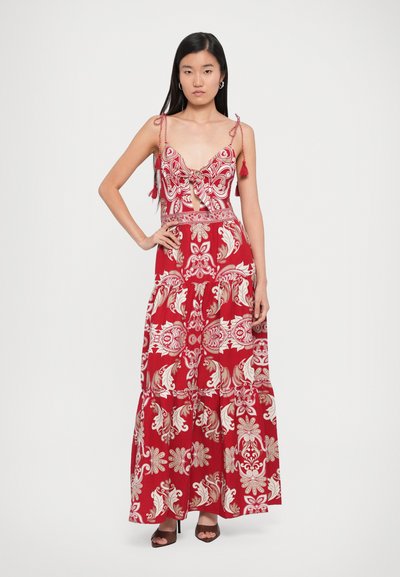 Red maxi dress with a floral and paisley print, featuring spaghetti straps, a front tie, and a tiered skirt. Material appears lightweight.