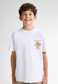 Witte katoenen t-shirt met een kleurrafische afbeelding van sinaasappels en de tekst "KEY WEST" in het roze. Korte mouwen en een ronde hals.