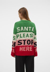 Gebreide trui met horizontale stripes in groen, roze en rood, met grote tekst: "SANTA PLEASE STOP HERE" in contrasterende kleuren.
