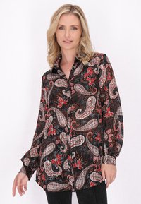 Camicetta nera con bottoni decorata con motivi paisley e floreali in rosso, bianco e grigio. Presenta maniche lunghe e un taglio rilassato.