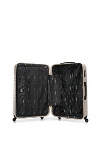 Maleta rígida color beige claro abierta, mostrando un interior negro con estampado, con compartimentos con cremallera y correas de sujeción ajustables.