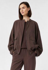 Braune Bomberjacke mit einer glatten, leicht strukturierten Oberfläche, mit einem Reißverschluss, seitlichen Taschen und einer lässigen Silhouette.
