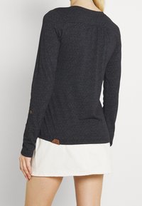 Langärmliges Hemd in Dunkelblau mit einem strukturierten geometrischen Muster. Verfügt über einen runden Ausschnitt und ein kleines Leder-Logoetikett am Saum.