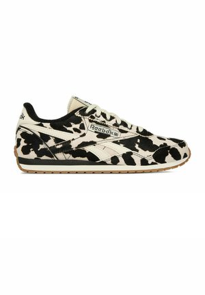 Buty sportowe Reebok z czarno-białym wzorem w krowie łatki, białymi sznurowadłami, gumową podeszwą i logo Reebok z boku, na języku i kołnierzu pięty.