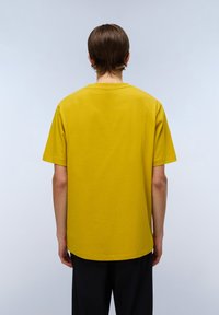 Kortærmet gul T-shirt lavet af bomuld, med rund hals og en afslappet pasform. Glat tekstur uden mønstre eller hardware-detaljer.