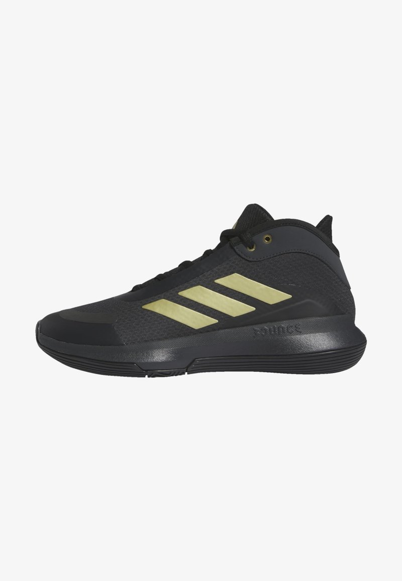 Chaussure de sport noire avec un design à trois bandes dorées sur le côté et une semelle rembourrée, vue de l'extérieur.